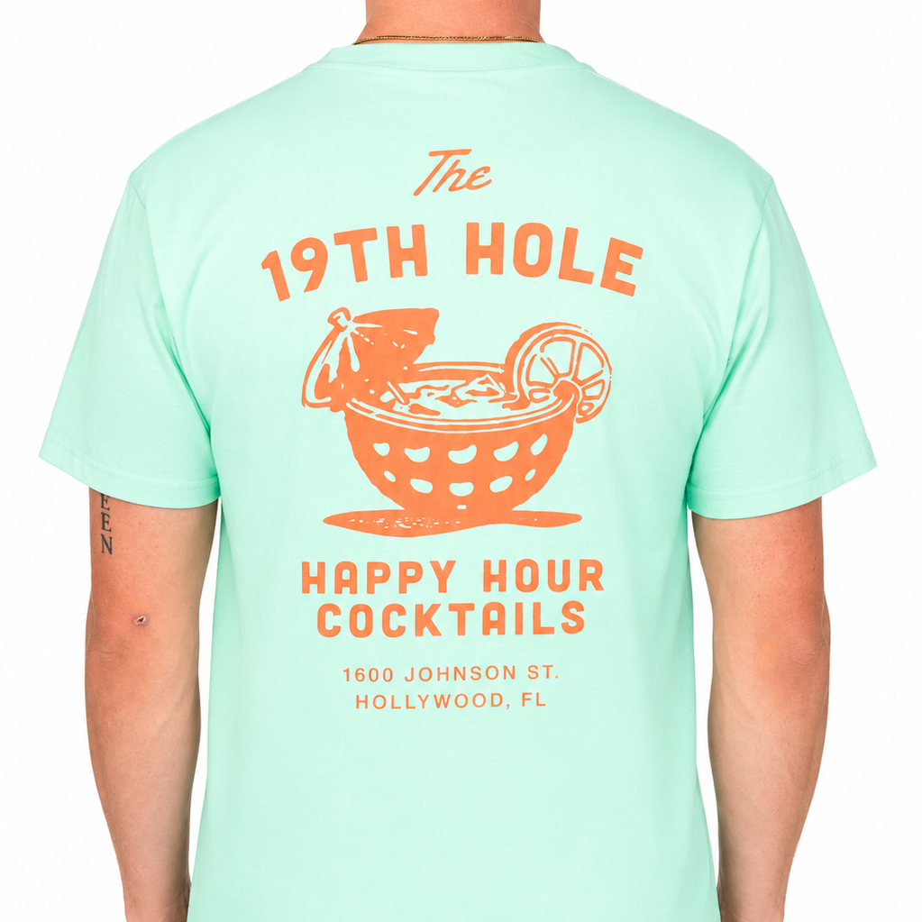 Back view of a male model wearing a mint green graphic t-shirt featuring a large coral “The 19th Hole Happy Hour Cocktails” design with a cocktail-in-a-golf-ball illustration and Hollywood, FL text. Studio product image on a clean white background.