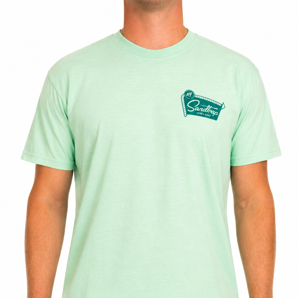 Male model wearing a mint green Sandtrap Après Golf t-shirt featuring a teal retro-inspired chest logo graphic. The shirt is shown from the front against a clean white studio background.