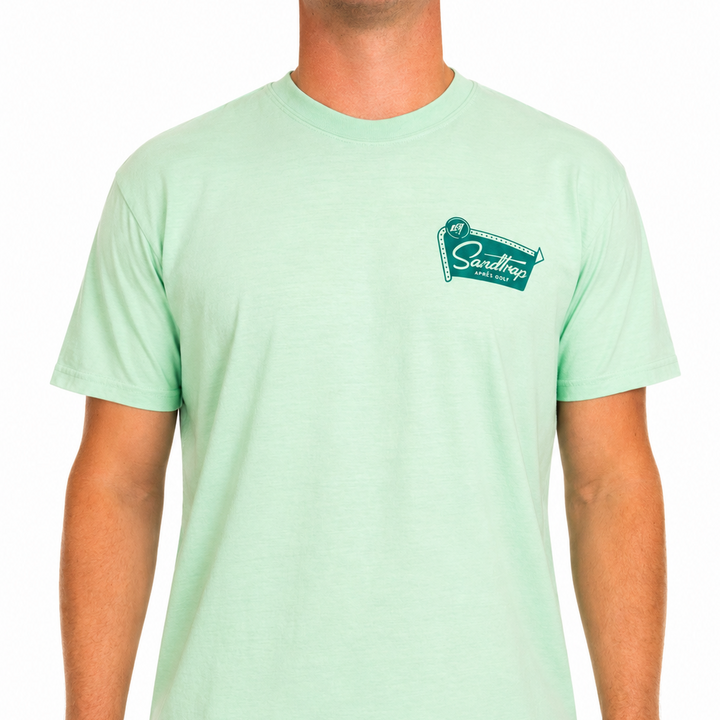 Male model wearing a mint green Sandtrap Après Golf t-shirt featuring a teal retro-inspired chest logo graphic. The shirt is shown from the front against a clean white studio background.