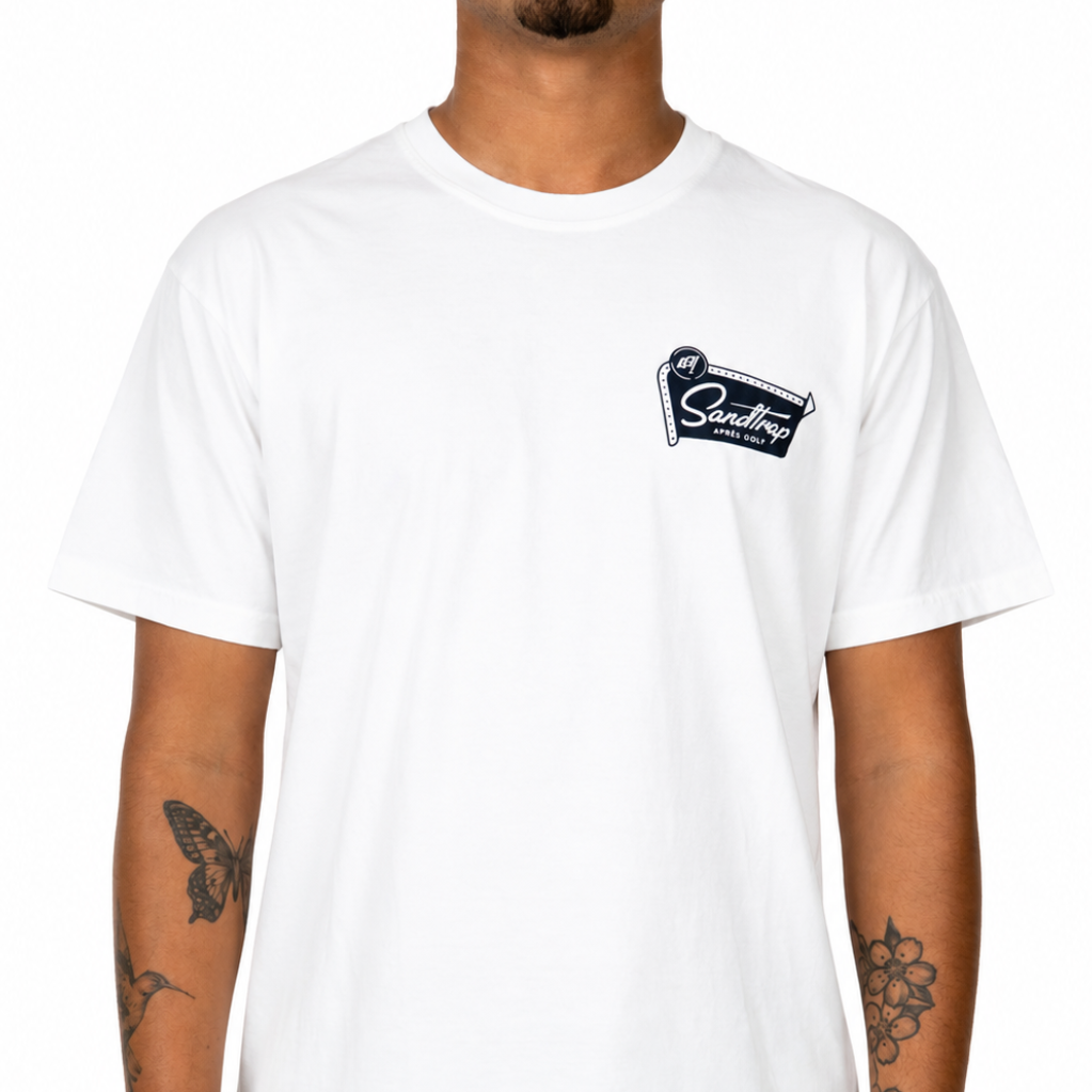 Male model wearing a white Sandtrap Après Golf t-shirt with a small black Sandtrap logo graphic on the left chest against a clean white background.