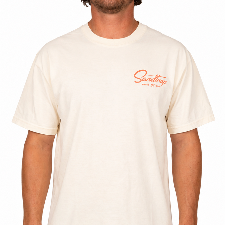 Man wearing a light cream t-shirt with a Sandtrap logo on a white background