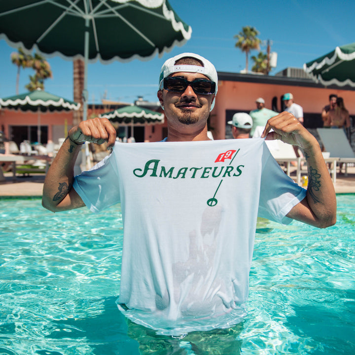 Male model wearing Amateurs white tee in pool, backwards hat, and sunglasses.
