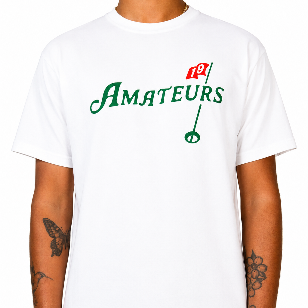 Male model wearing the white Amateurs Sandtrap T-shirt featuring a green "Amateurs" wordmark and red golf flag graphic on the chest against a clean studio background.