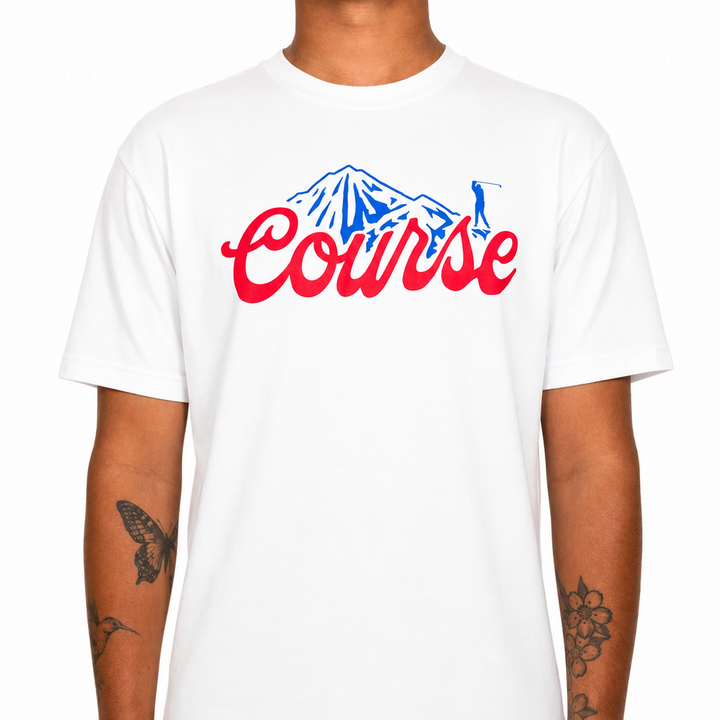Male model wearing a white Sandtrap T-shirt featuring a large red “Course” script graphic with a blue mountain illustration across the chest. The relaxed-fit tee is shown against a clean studio background to highlight the fit, color contrast, and front artwork.